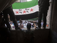 Free Syrian Army rebels hold a revolutionary flag during a demonstration in the Bustan al-Qasr neighborhood of Aleppo, Syria