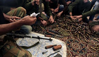 Free Syrian Army fighters clean their weapons and check ammunition