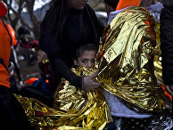 A boy is wrapped in an emergency thermal blanket after arriving on a rubber boat at a beach on the northern coast of Lesbos, Greece