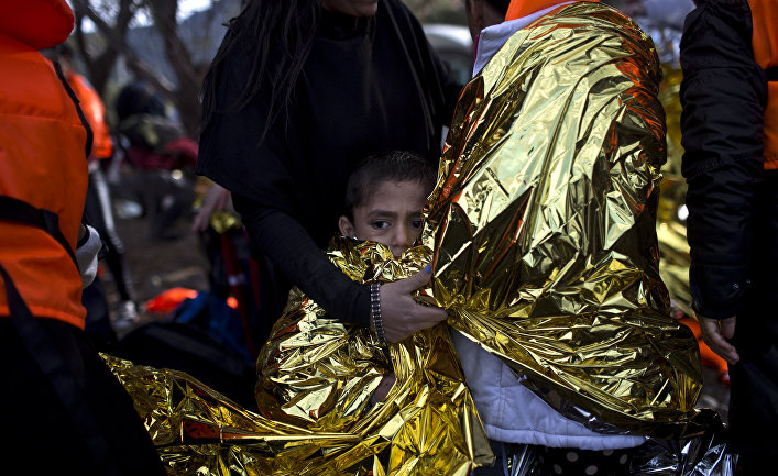 A boy is wrapped in an emergency thermal blanket after arriving on a rubber boat at a beach on the northern coast of Lesbos, Greece