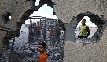 Palestinian Suma Abu Mahsen, 7, stands by a damaged wall of a house following an overnight Israeli missile strike