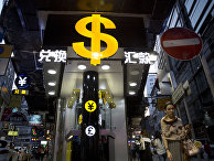 A woman walks near a dollar sign outside a money exchange shop in Hong Kong
