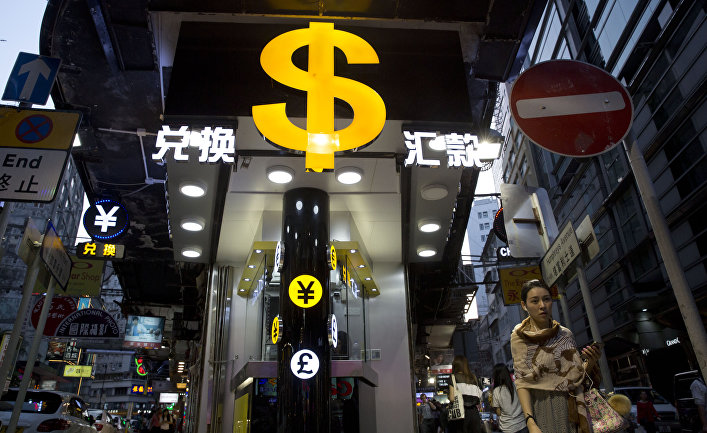 A woman walks near a dollar sign outside a money exchange shop in Hong Kong