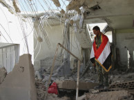 Syrian soldier wrapped in a Syrian flag stands in a damaged house in Achan, Hama province, Syria.
