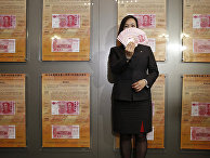 A staff member displays the new version of the 100-yuan RMB (US 15.7 dollars) banknotes for photographers at the Bank of China Tower in Hong Kong