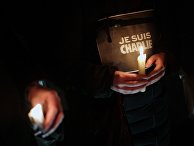 People hold candles and a placard reading "I am Charlie" as they gather to commemorate the victims of a terror attack against French satirical newspaper Charlie Hebdo in Paris