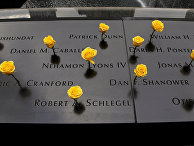 Yellow roses stand wedged into names carved in the granite at the South Pool of the National September 11 Memorial