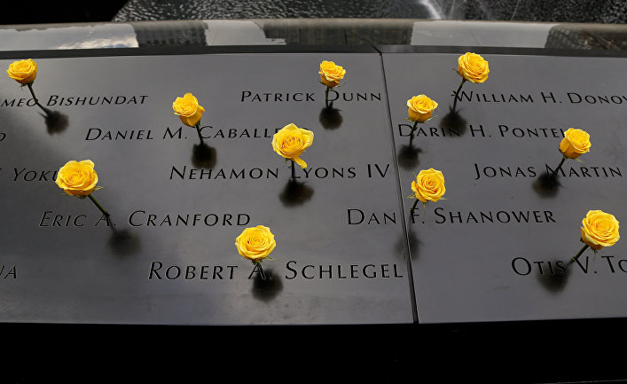 Yellow roses stand wedged into names carved in the granite at the South Pool of the National September 11 Memorial