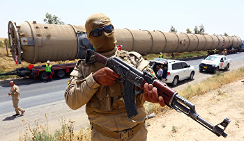A Kurdish Peshmerga fighter stands guard as new equipment arrives at Kalak refinery on the outskirts of Irbil, Iraq