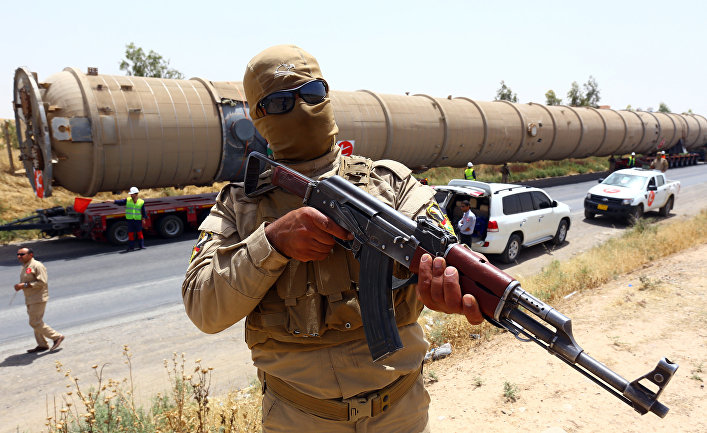A Kurdish Peshmerga fighter stands guard as new equipment arrives at Kalak refinery on the outskirts of Irbil, Iraq