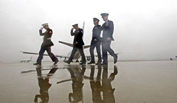 Military personnel hold their hats as they walk away from Air Force One, with President Barack Obama aboard, as he departs from Andrews Air Force Base, Md