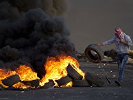 A Palestinian youth burns tires during clashes following a demonstration to demand the release of bodies of Palestinian attackers being held by Israeli authorities, in the West Bank city of Ramallah