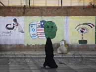 A woman walks past anti-Saudi and US graffiti sprayed on a wall of the closed Saudi embassy in Sanaa, Yemen