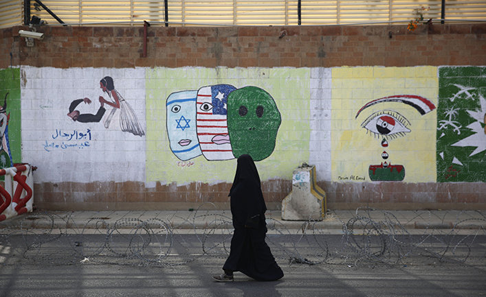A woman walks past anti-Saudi and US graffiti sprayed on a wall of the closed Saudi embassy in Sanaa, Yemen