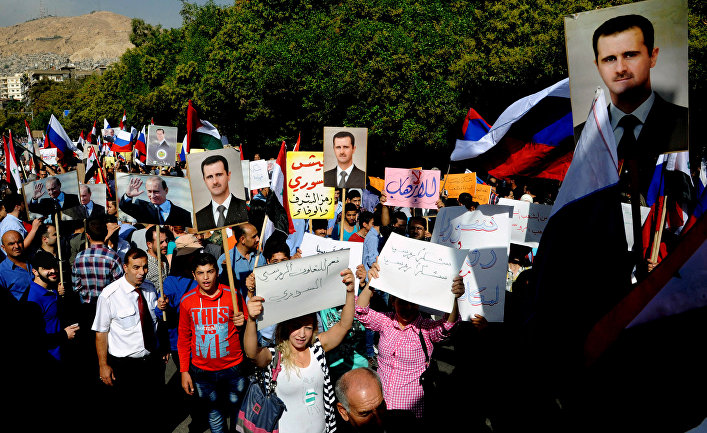 Syrians holding photos of Syrian President Bashar Assad and Russian President Vladimir Putin, during a protest to thank Moscow for its intervention in Syria