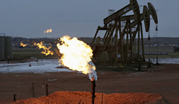 Oil pump jacks work behind a natural gas flare near Watford City, N.D.