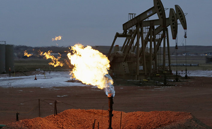 Oil pump jacks work behind a natural gas flare near Watford City, N.D.