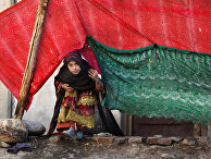 An internally displaced girl peeks from a tent after her family left their village in Rodat, Afghanistan. At least 25,200 families have been displaced across the province by Islamic State militants